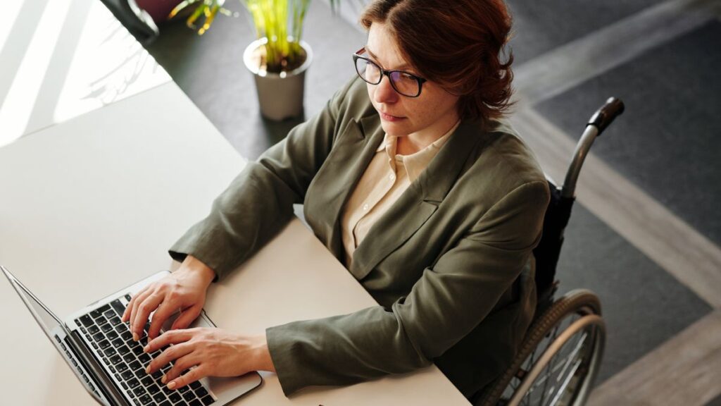 Woman in a wheelchair working on a laptop at an office desk
